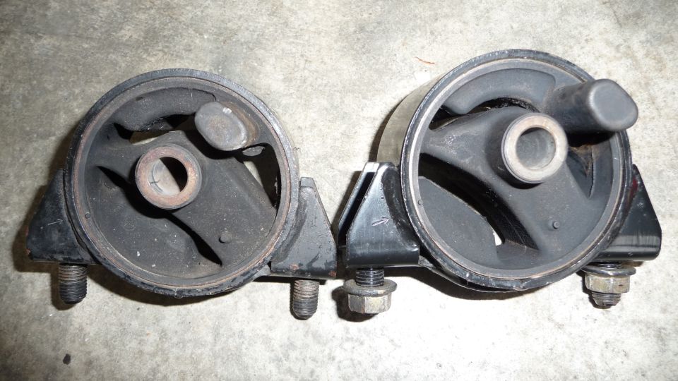 Two black rubber engine mounts with metal brackets and bolts
