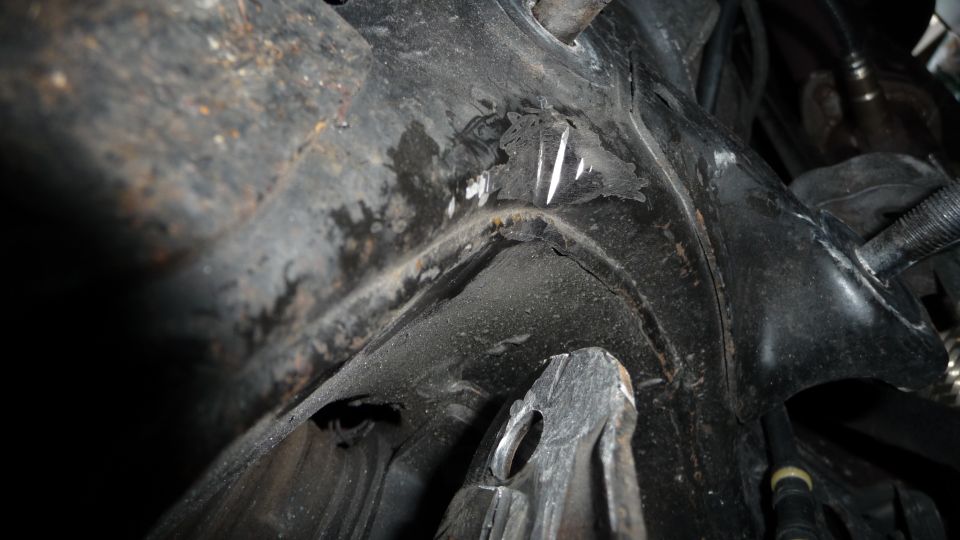 Close-up of damaged metal frame structure, possibly from a car's undercarriage