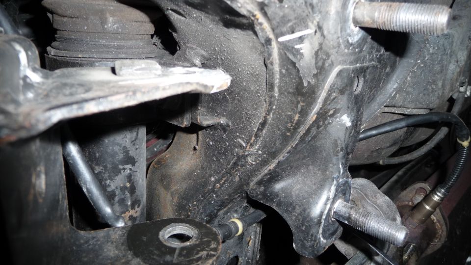 Close-up of a car's engine mount bracket and suspension components, showing metal brackets and bolts