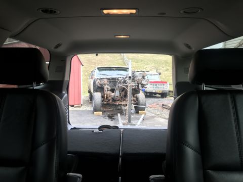 1992 Ford Bronco - View from inside a vehicle shows a disassembled truck on a hoist, with another truck parked behind it.