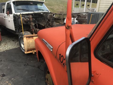 1992 Ford Bronco - Two older Ford trucks are parked outside, one is an orange F-350 and the other is a white truck missing its engine.