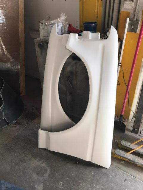 1992 Ford Bronco - A white fender part is shown in a workshop setting, with tools and supplies in the background.