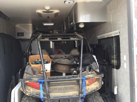 2010 Ford E250 - A Polaris UTV is loaded into a trailer, showing its rear end and roll cage.