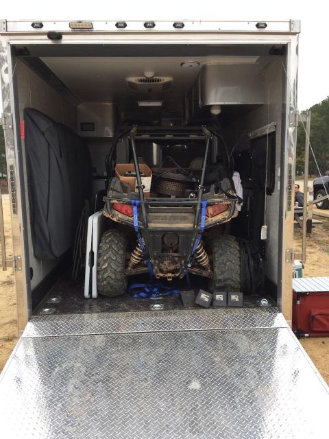 2010 Ford E250 - A side-by-side ATV is secured inside an open trailer, ready for transport.