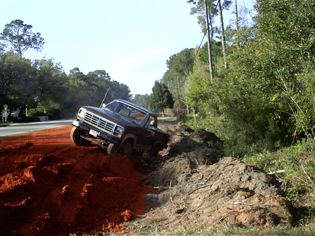 Brown pickup truck driving off-road on a dirt hill