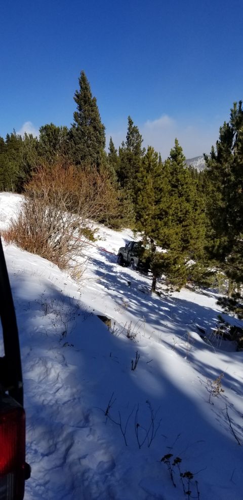 1996 Ford Bronco - A vehicle navigates a snow-covered mountain path under a clear blue sky.