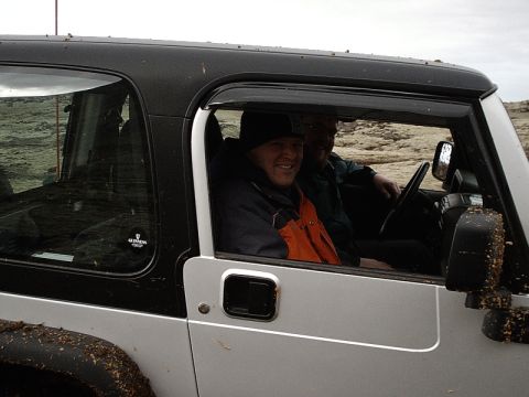 1996 Ford Bronco - Two men are inside a silver Jeep Wrangler with a black hardtop, ready for an off-road adventure.