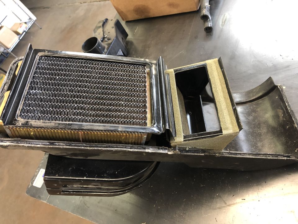 Car heater core with fins and blower motor housing. Foam insulation is visible
