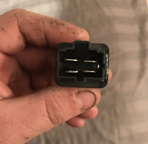 1995 Ford Bronco - A hand holds a black electrical connector with four visible metal pins.