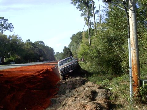 1985 Ford Bronco - A truck is stuck in a ditch beside a road construction area and a utility pole.