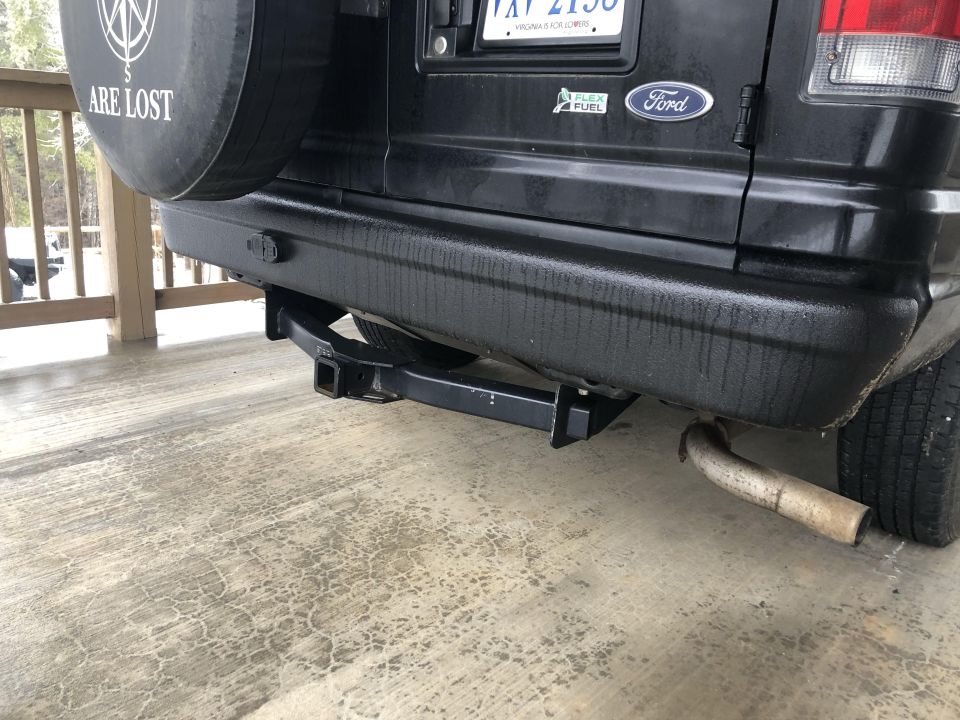 Rear view of a black Ford van with trailer hitch and spare tire.