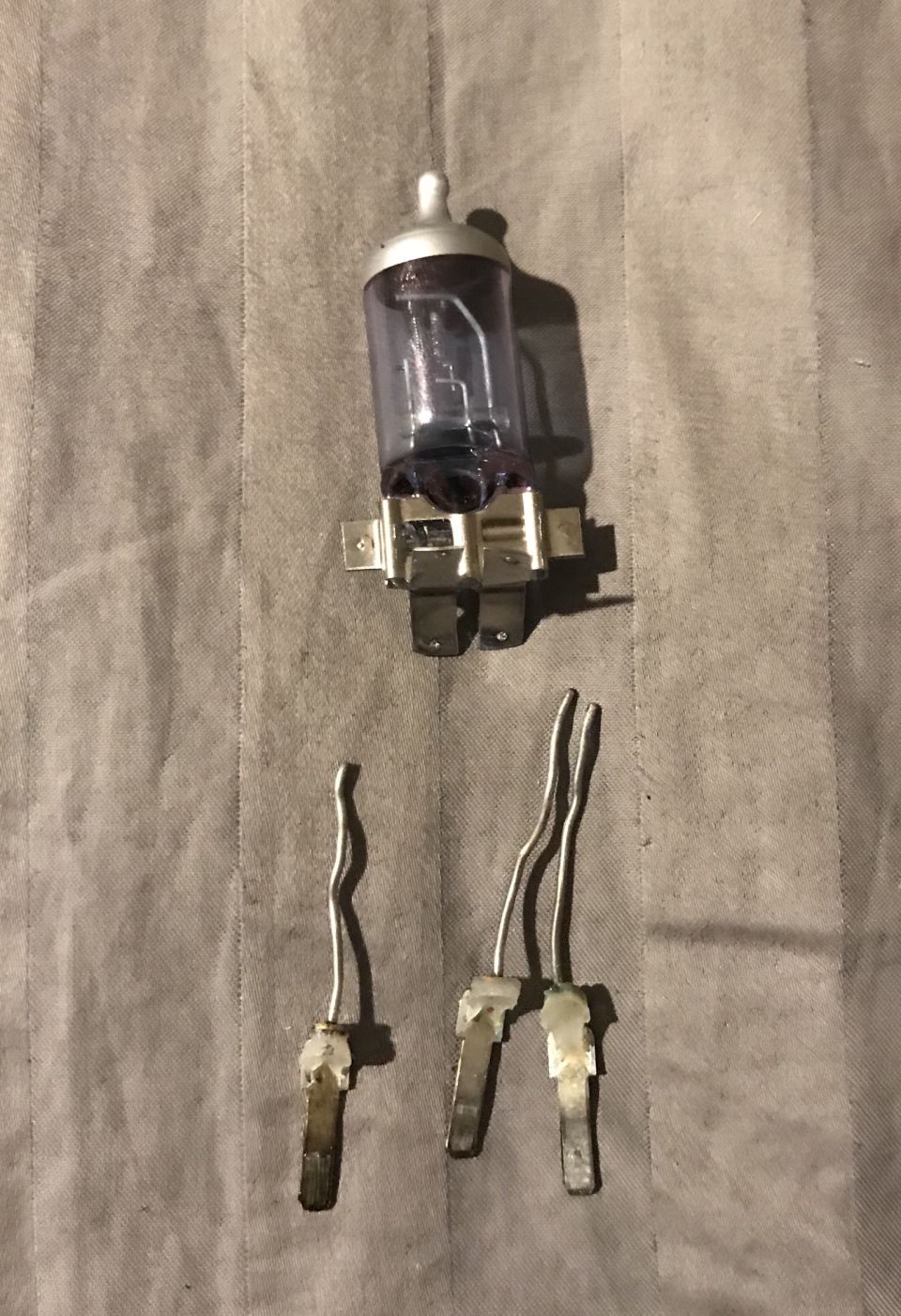 Two automotive headlight bulbs, one assembled and one disassembled.