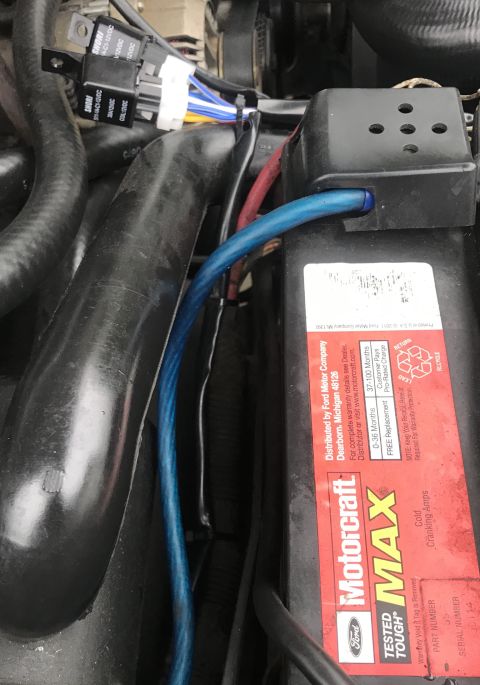 1995 Ford Bronco - A close-up view shows a blue wire running along the side of a black Motorcraft battery in an engine bay. Several other wires and hoses are…