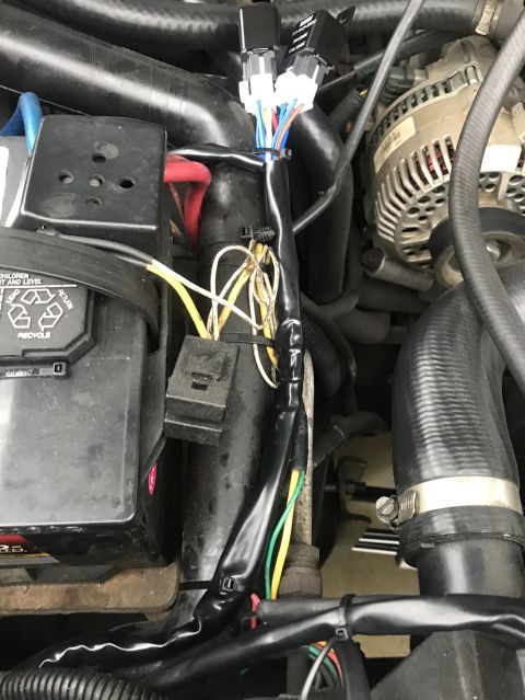1995 Ford Bronco - A close-up view of the engine bay of a 1995 Ford Bronco, showing wiring harnesses, a battery, and parts of the alternator and radiator hose…