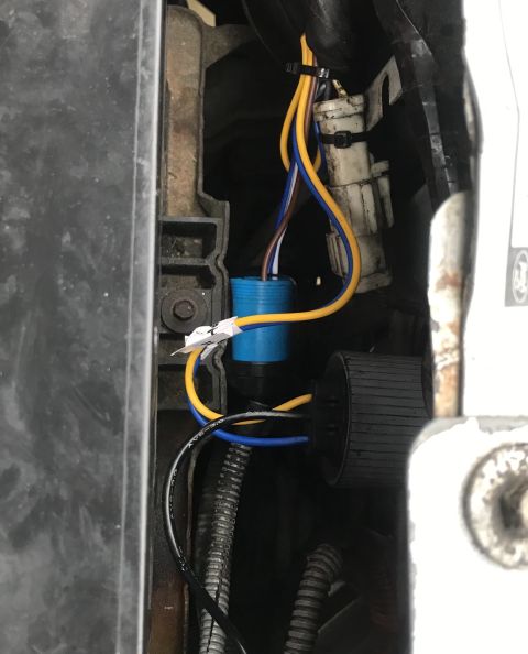 1995 Ford Bronco - Close-up view of automotive wiring harness with a blue cylindrical component and a black connector. Multiple colored wires, including yello…