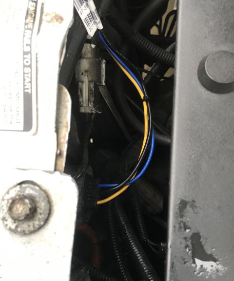 1995 Ford Bronco - A close-up view of wiring harness connectors and cables under the hood of a vehicle. A white connector with blue and yellow wires is visibl…