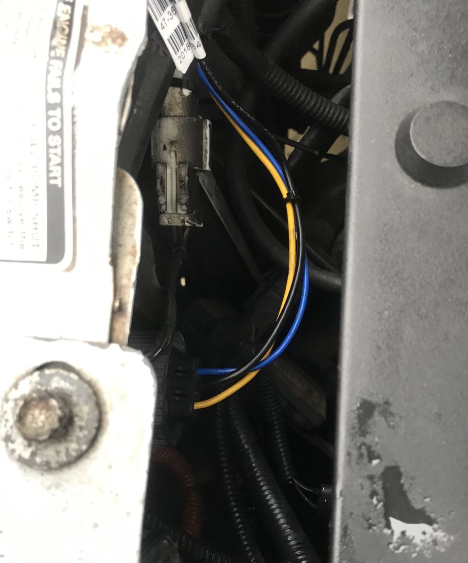 Close-up of vehicle wiring harness connectors and cables under the hood.