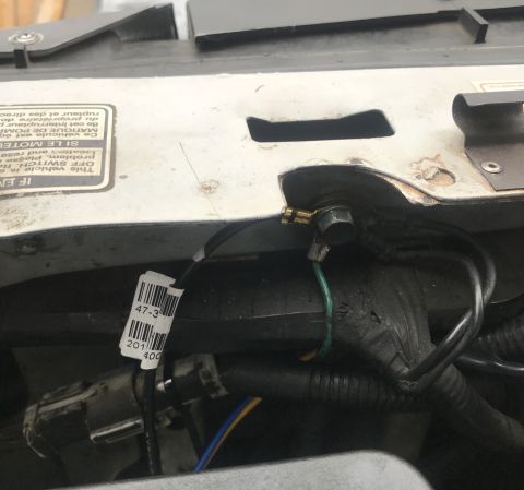 1995 Ford Bronco - A close-up view shows a ground wire connected to a bolt on the vehicle's body. A white label with black text and a barcode is visible on a…