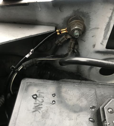 1995 Ford Bronco - A close-up view of electrical connections and wiring in a vehicle's engine bay, including a ground stud and a black wire with a gold connec…