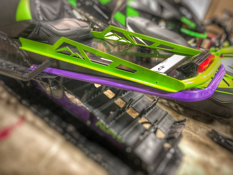 Snowmobile rear section with green and purple trim and track visible.