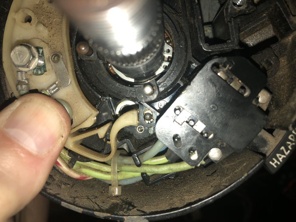 Close-up of vehicle steering column interior with electrical components and hazard switch.