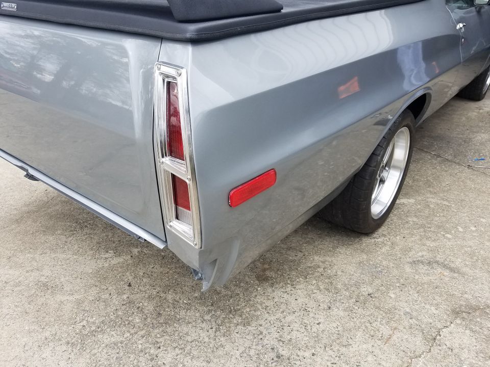Gray pickup truck rear driver's side corner with taillight and side marker light