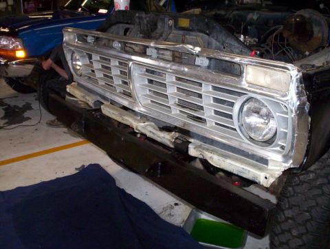 1978 Ford Bronco - The front end of a 1978 Ford Bronco shows damage to the bumper and grille area, indicating it is undergoing repairs.