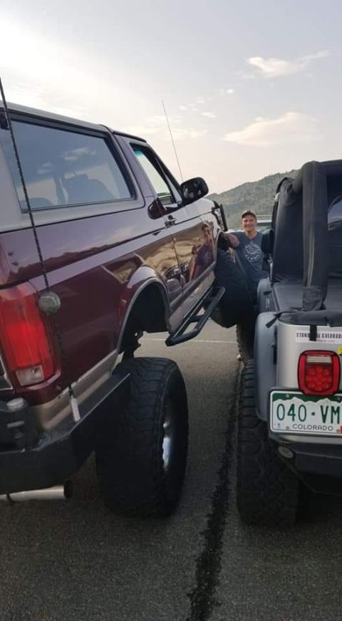 1996 Ford Bronco - A man leans against a lifted Jeep Wrangler with a large tire, standing next to a lifted maroon Ford Bronco. The Bronco is viewed from the r…