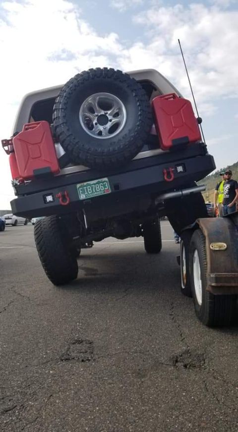1996 Ford Bronco - The rear of a lifted Ford Bronco is shown, equipped with a spare tire, two red jerry cans, and a custom bumper with tow hooks. A trailer is…