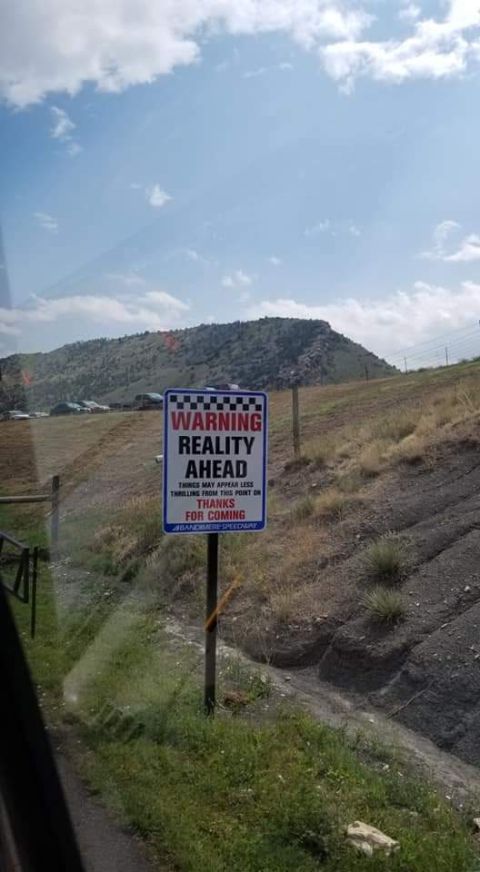 1996 Ford Bronco - A sign reads "WARNING REALITY AHEAD THINGS MAY APPEAR LESS THRILLING FROM THIS POINT ON THANKS FOR COMING ABANDONED SPEEDWAY". The sign is…