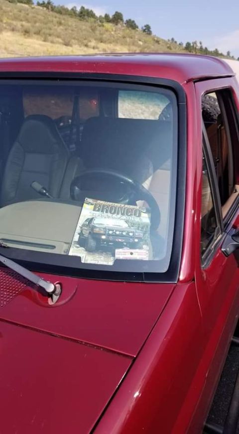 1996 Ford Bronco - A magazine featuring a Ford Bronco is placed on the dashboard of a red Ford Bronco. The vehicle is parked outdoors with a dry, grassy hills…