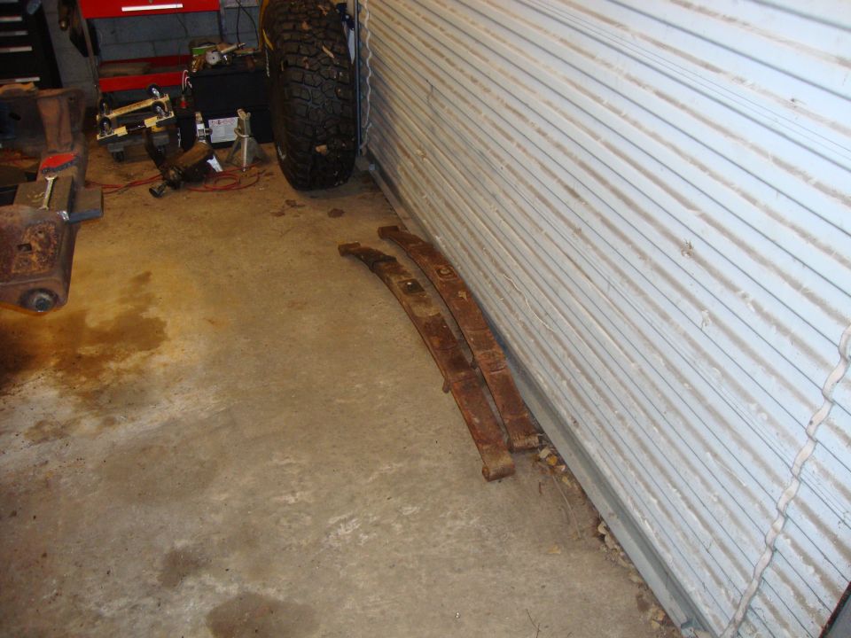 Two rusty leaf springs on a concrete floor.