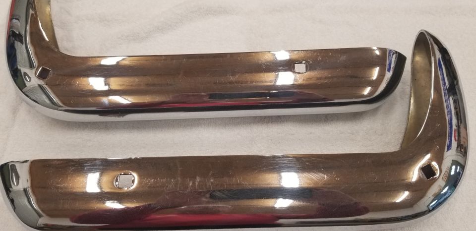 Two chrome bumper guards with square cutouts on a white surface.
