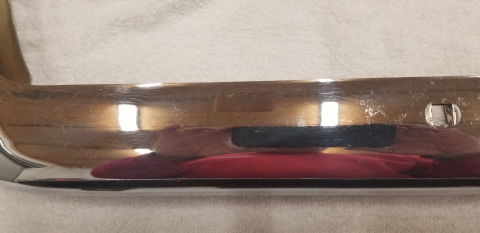 Chrome bumper with scratches and a square hole.
