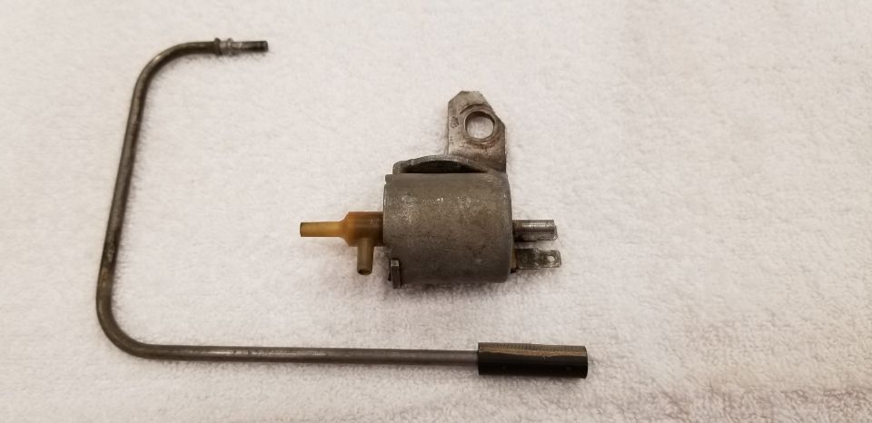 Metallic vacuum switch and bent metal tube with rubber end on white surface