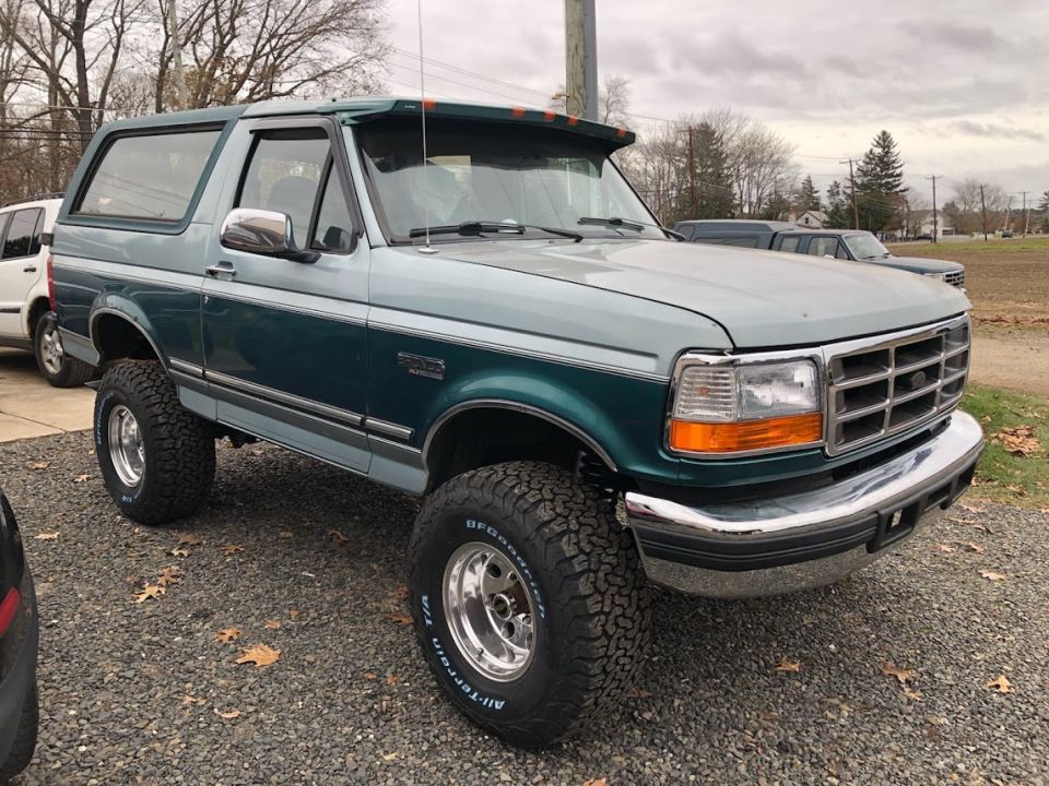 1996 Ford Bronco in teal and light blue with off-road tires.