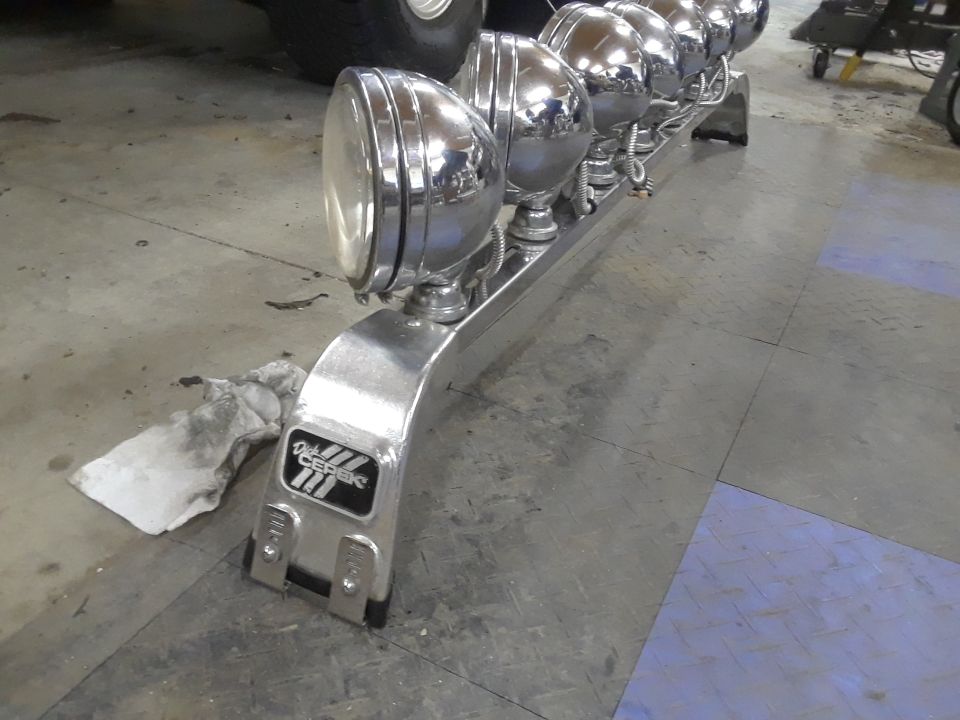 Chrome light bar with six headlights and Dick Cepek logo on a vehicle.