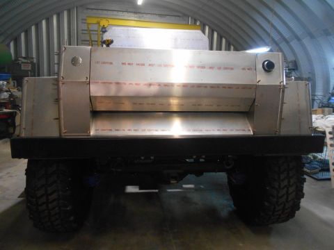 1992 Ford Bronco - Rear view of a custom-built vehicle with large off-road tires, featuring a brushed aluminum body with visible lot numbers stamped on panels…