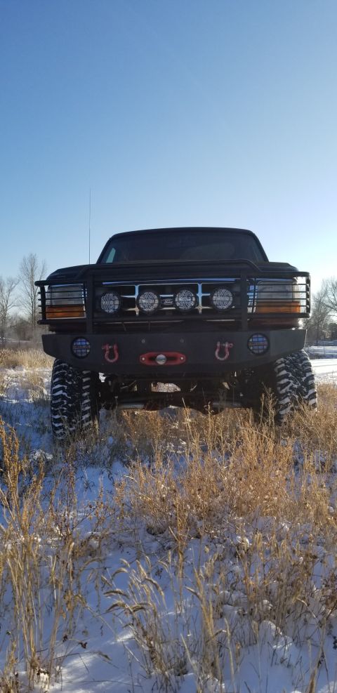 1996 Ford Bronco - A lifted 1996 Ford Bronco is parked in a snowy field with dry grass in the foreground. The front of the vehicle features a black brush guar…