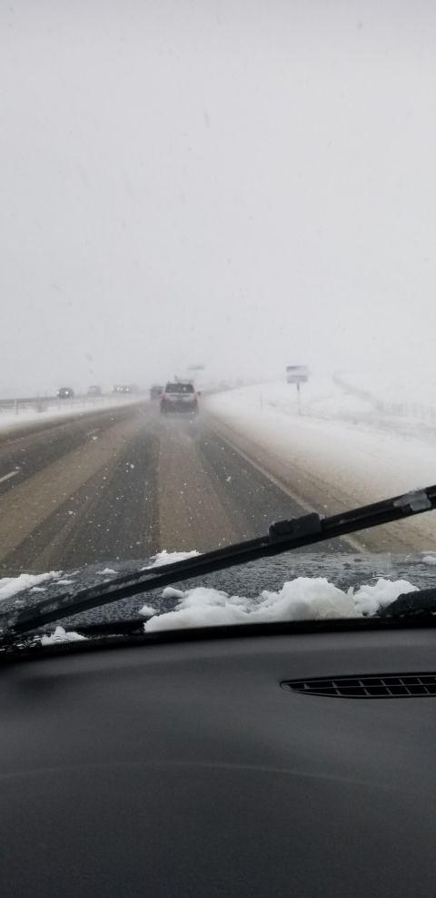 1996 Ford Bronco - View from inside a vehicle driving on a highway during a snowstorm. Snow is accumulating on the windshield and the road is wet and slushy.