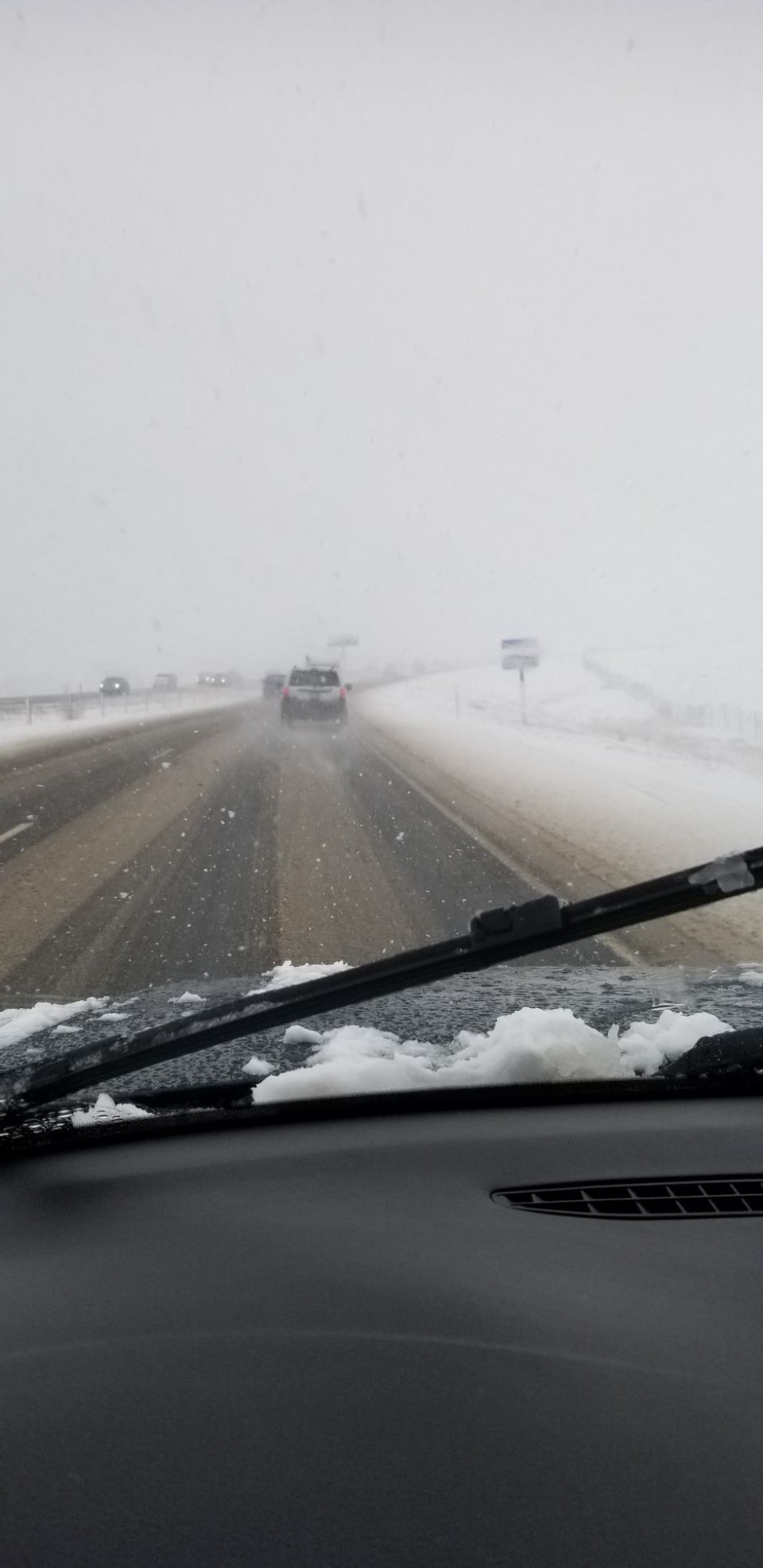 Driving on a highway in a snowstorm, view from inside the car.