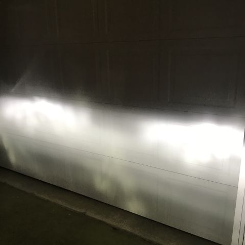 1995 Ford Bronco - The bright headlights of a vehicle illuminate a garage door. The light pattern shows a distinct cutoff, indicating proper aiming.