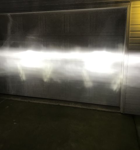 1995 Ford Bronco - The bright headlights of a vehicle are illuminating a garage door, creating a sharp horizontal beam with some diffusion and shadow patterns…