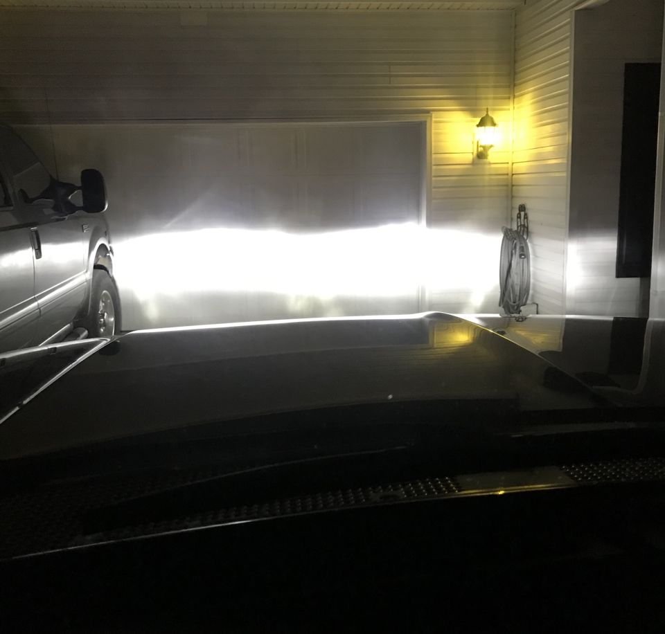 Vehicle headlights illuminating a garage door, with a hose reel on the wall.