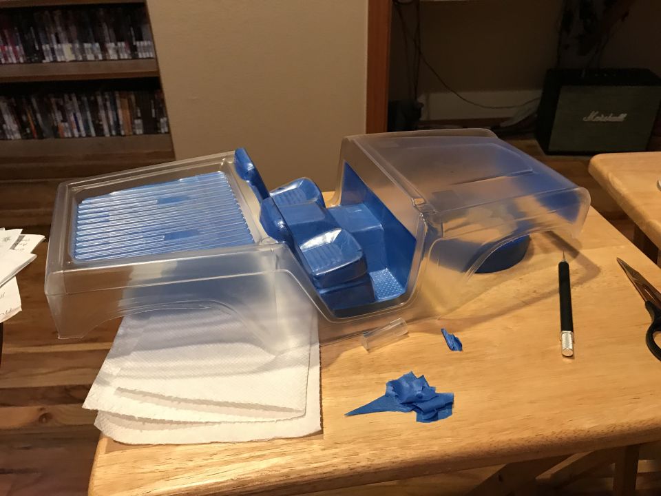 Clear plastic RC car body with blue interior on a wooden table.