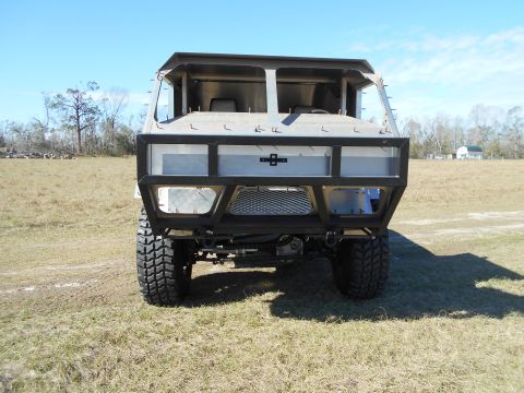 1992 Ford Bronco - Front view of a custom-built, unfinished vehicle with a large metal bumper and exposed cab structure. The vehicle is parked on a grassy fie…