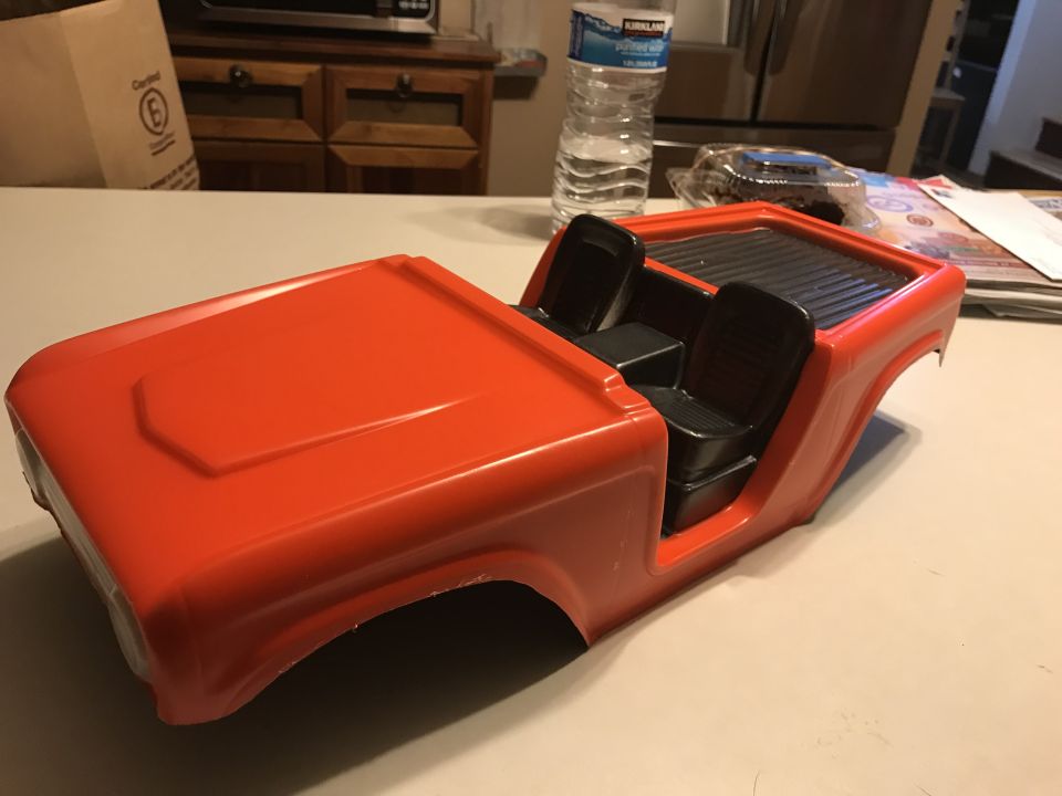 Orange plastic Jeep body with black seats, front 3/4 view.