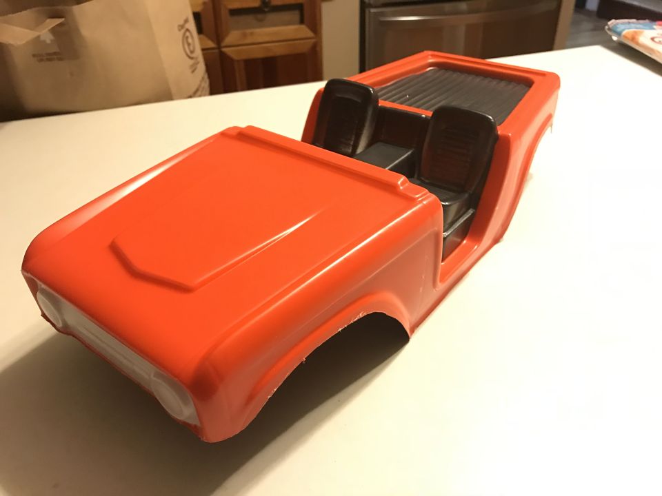 Orange plastic 1989 Ford Bronco model body with black interior seats.