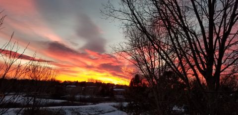 1996 Ford Bronco - A dramatic sunset paints the sky with vibrant hues of orange, yellow, and pink, casting long shadows over a snow-dusted landscape and silho…