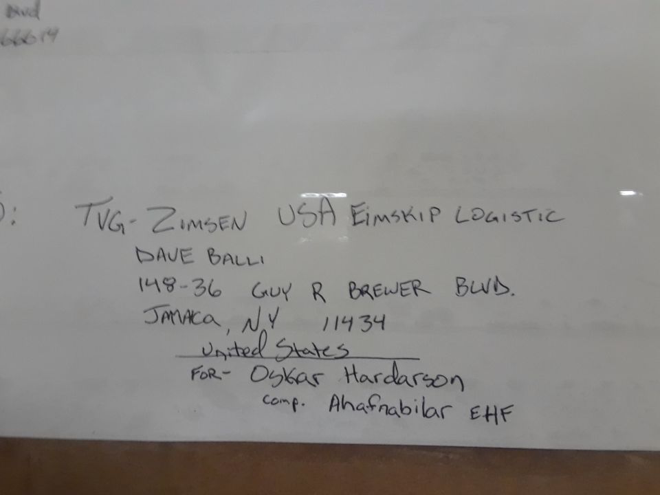 Handwritten shipping information on a whiteboard.